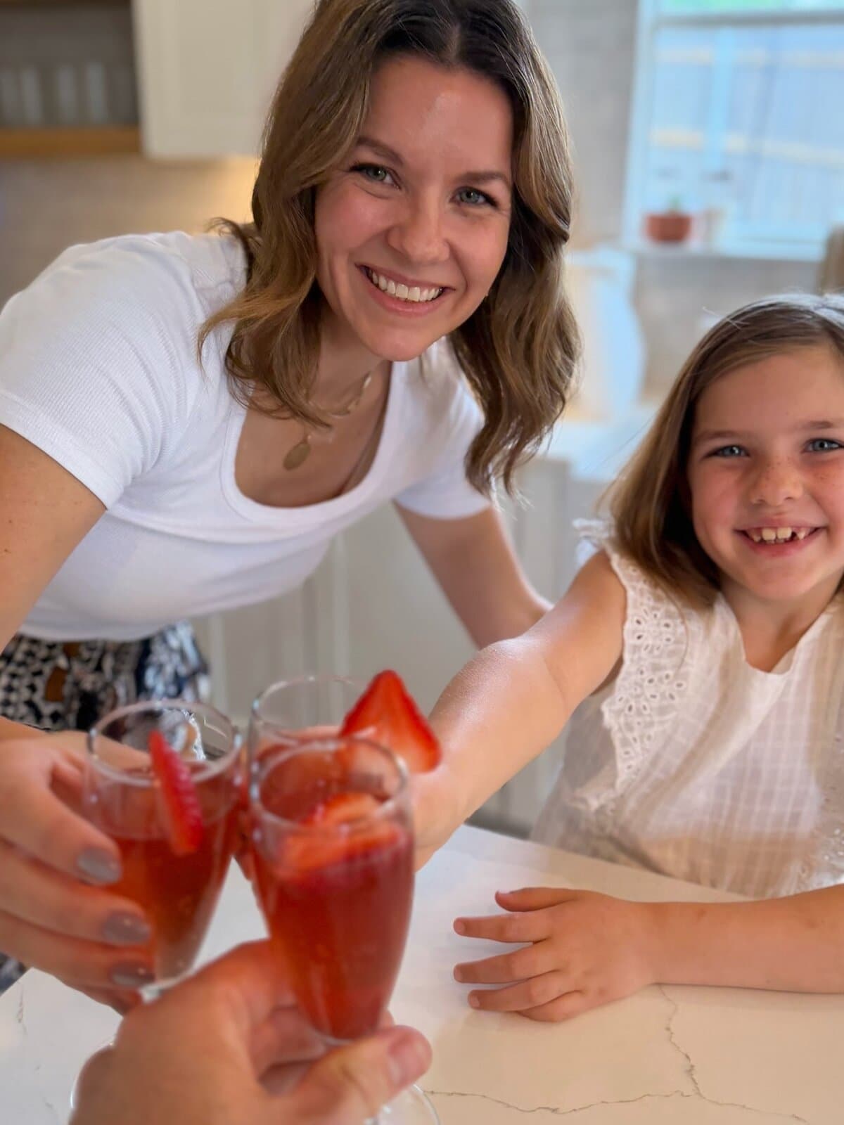 Mom and daughter toasting with Strawberry Mimosa mocktails in the kitchen