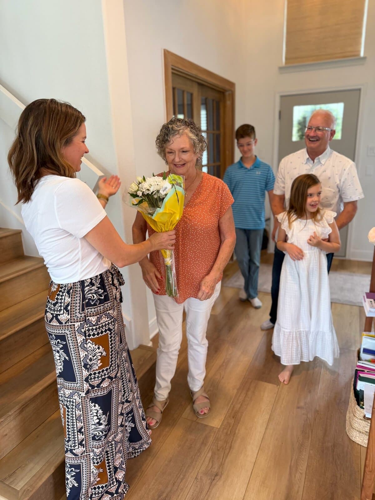 Family surprising Grandma with flowers in the entryway on Mother's Day
